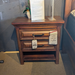 Wooden nightstand with a tag on a carpeted floor