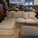 Beige sectional sofa with ottoman in a furniture store setting