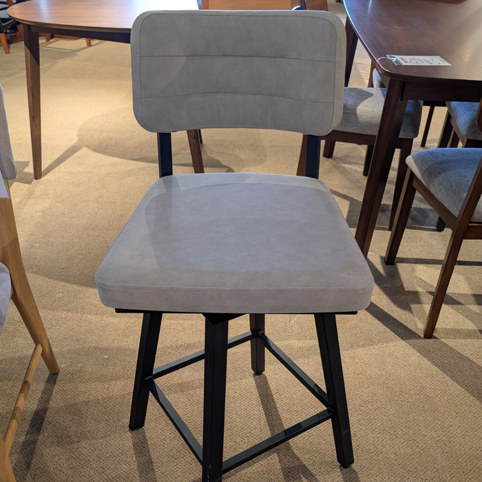 Gray cushioned bar stool with black legs in a showroom setting