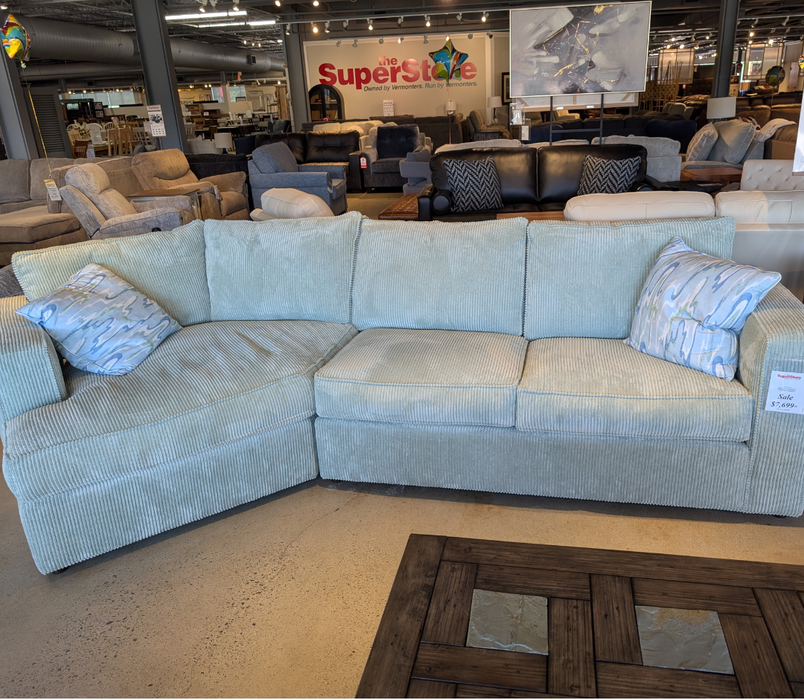 Sectional sofa in a furniture store with 'SuperStore' branding in the background.